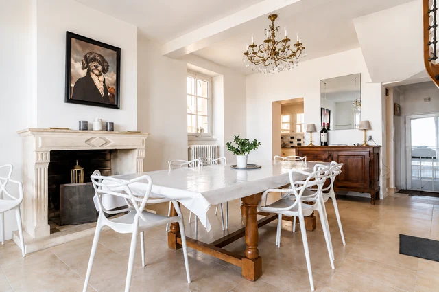 Salle à manger blanche avec grande table, cheminée et portrait de chien