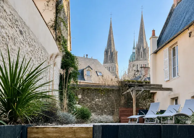 La terrasse de Baya House, ses murs de pierre et la cathédrale de Bayeux