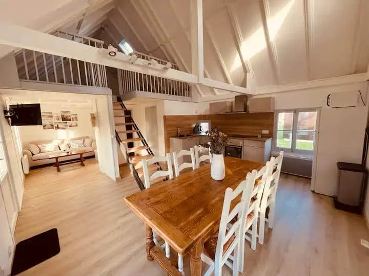 Pièce de vie de Beach House, avec table en bois et mezzanine blanche