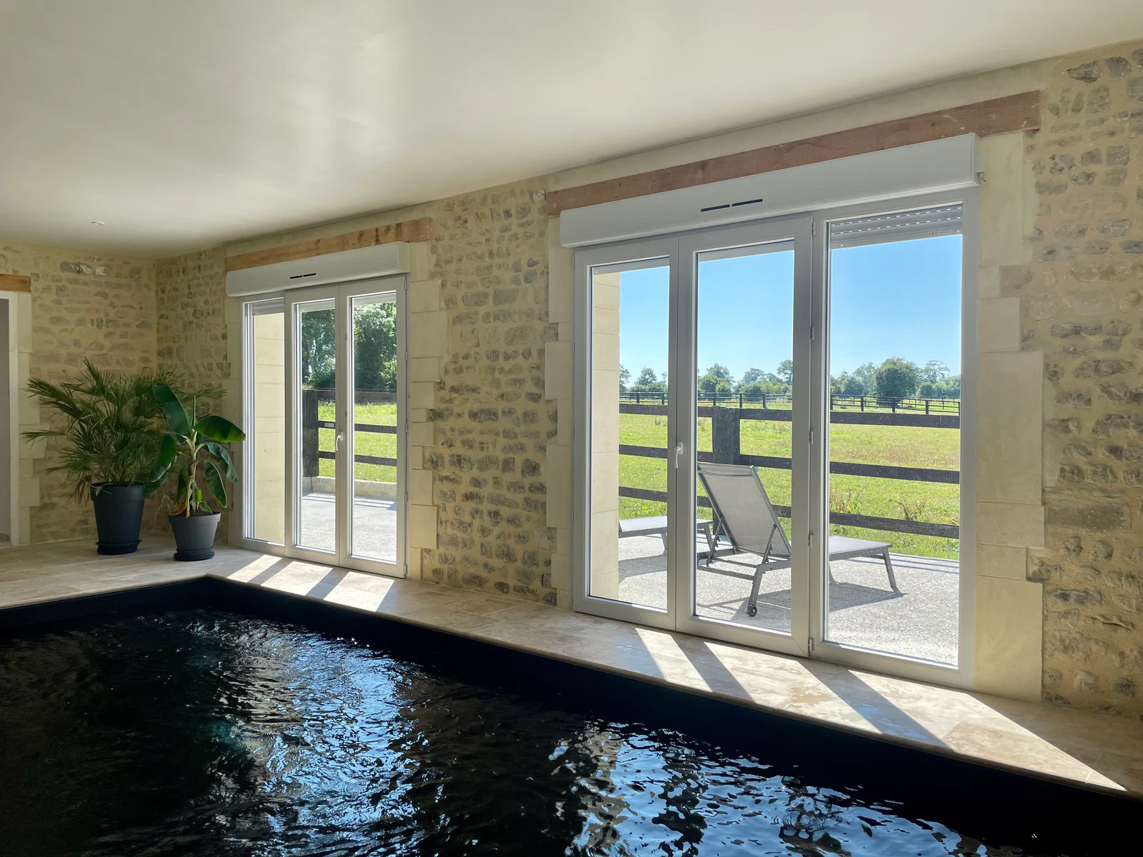 Piscine intérieure du Logis Courtelay, entre murs de pierre et vue sur la prairie