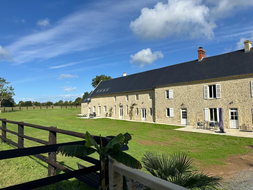 Façade en pierre du Logis de Courtelay, terrasse et pelouse devant la maison