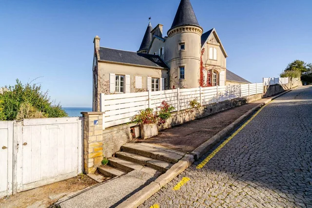 La maison Vent Debout et ses tourelles en pierre, avec la mer à Arromanches