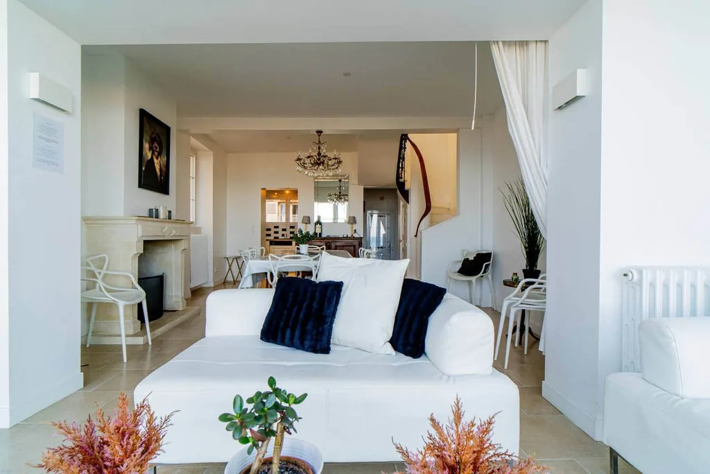 Salon de Villa Bellevue avec canapé blanc, cheminée et salle à manger en arrière-plan
